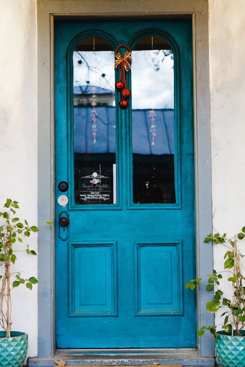 Wood door painted blue with double glass panes and black hardware.