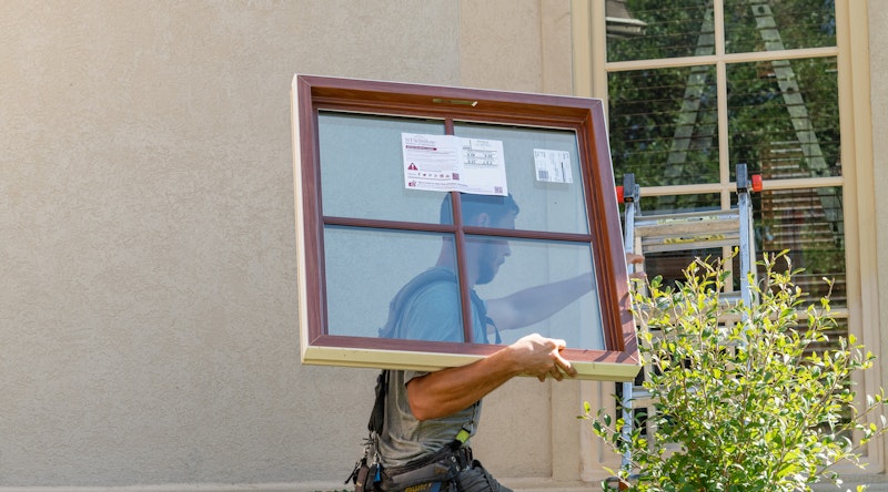 Brennan window technician carrying a window for installation. Image Credit: Brennan Enterprises, Tim Marek.