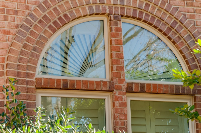 Two quarter round picture windows over two windows below on brick building.