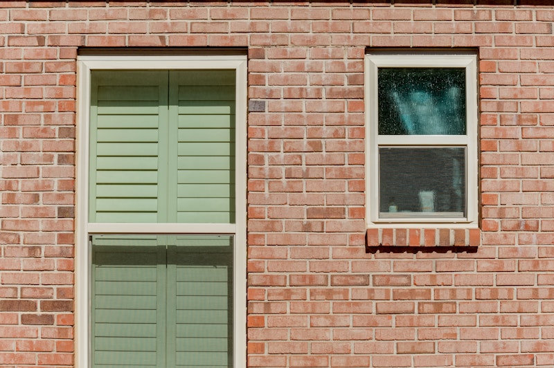 Photo of two single hung vinyl windows, one with textured privacy glass.