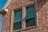 Close-up of two clay double hung windows on house with brick veneer.