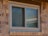 Close-up of tan sliding window on house with light brown brick.