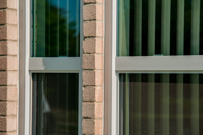 Close-up of vinyl windows installed in brick building.