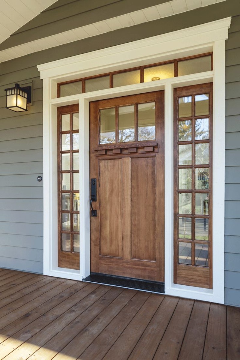 Custom wood front door with dark hardware, glass with grids on top part of door, sidelites and transom with grids