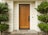 Wood front door with black hardware on house with light siding.