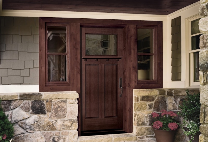 Two double-hung windows finished with a deep stain between a wood door with a large glass lite.